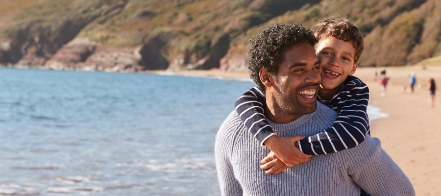 Man giving son a piggy back on the beach